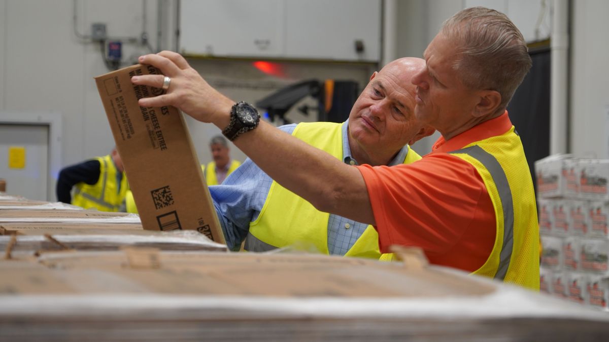 Two Individuals Reading a Box in Warehouse
